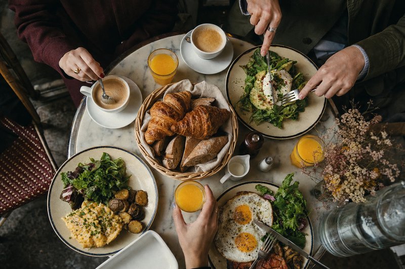 Weekend brunch table at a Paris café with eggs, viennoiserie, fresh orange juice and café crème