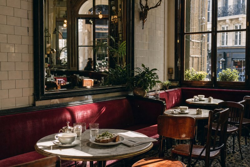 Marble tables and rattan chairs at a Paris corner brasserie in the Marais, set for morning service
