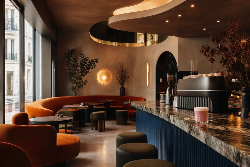 Futuristic curved café interior in warm orange tones with sculptural seating and a polished espresso bar
