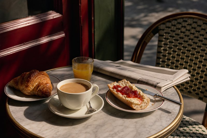 Classic Paris café breakfast with café crème, split baguette tartine, butter, jam and fresh orange juice on a marble table