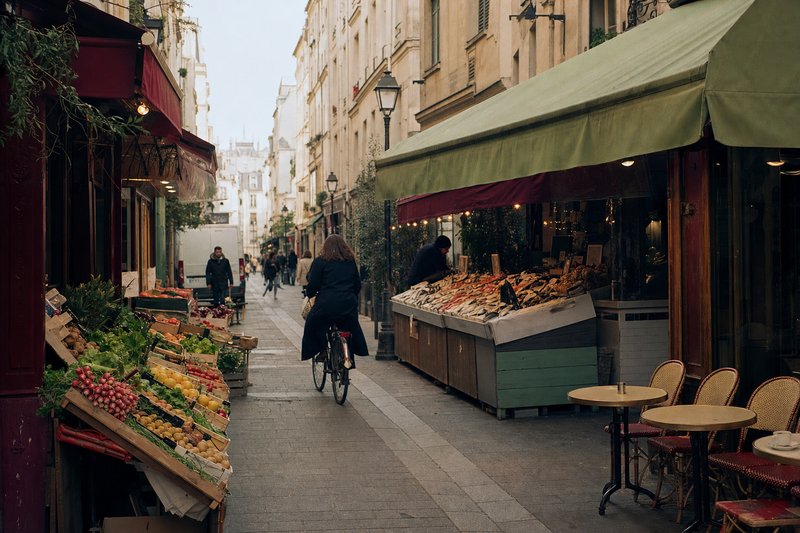 Morning on Rue de Bretagne in the Marais with market crates, shop awnings and café terraces along the street